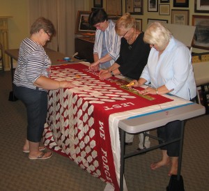 Members of Vintage Gatherers-Linda Katherman, Karen Shipton, Lana Miller and Barbara Stiner-put the finishing touches on this Memorial quilt which will hang in the Hall of Heroes during the World War II Exhibit at Lycoming Mall.